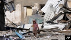Un niño palestino pasa junto a edificaciones destruidas durante el bombardeo israelí de la Franja de Gaza en Deir al Balah el sábado 13 de enero de 2024.