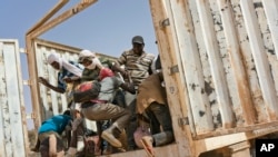 FILE - Migrants climb into a truck to head north into Algeria at the Assamaka border post in northern Niger on June 3, 2018.