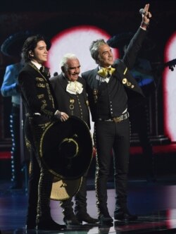 En esta fotografía del 14 de noviembre de 2019 Vicente Fernández, centro, su hijo Alejandro Fernández, derecha, y su nieto Alex Fernández saludan su presentación en los Latin Grammy en el MGM Grand Garden Arena en Las Vegas.