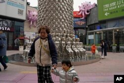 Algunas personas caminan por un distrito comercial en Beijing, el miércoles 15 de noviembre de 2023.