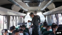 This handout photo taken and released on November 18, 2023 by the Royal Thai Army shows Thai military personnel with some of the 41 Thai nationals on a bus to Mae Sai after they returned to Thailand after being trapped in Myanmar.