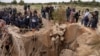 Warga masyarakat menyaksikan Menteri Kepolisian Afrika Selatan, Senzo Mchunu, memeriksa bagian luar terowongan tambang tempat ratusan penambang ilegal diperkirakan bersembunyi di bawah tanah, di Stilfontein, Afrika Selatan, 15 November 2024. (Ihsaan Haffejee/REUTERS)